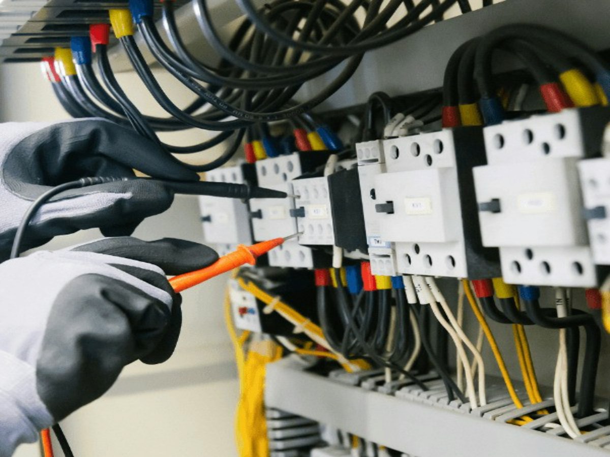 Technicien mesurant la tension aux bornes de contacteurs avec un multimètre
